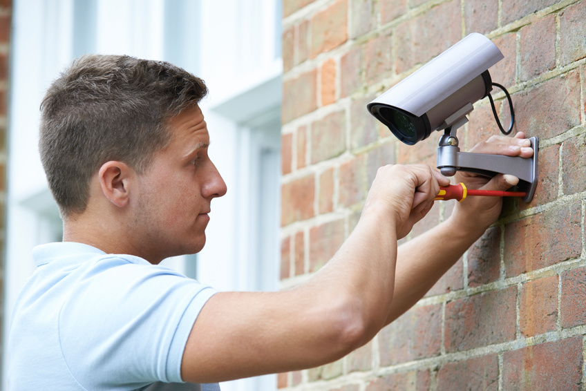 Security Consultant Fitting Security Camera To House Wall
