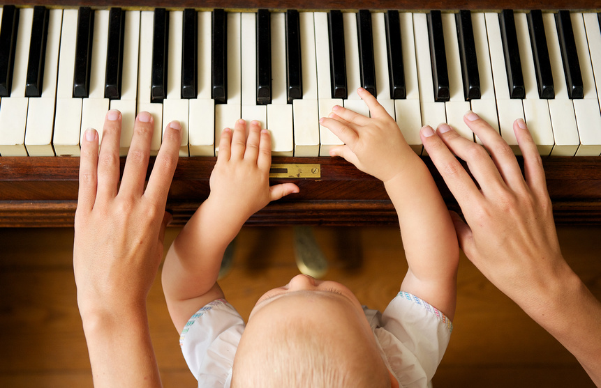 Baby learning to play piano with mother