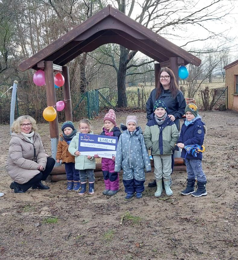 Scheckübergabe bei einer kurzen Regenpause in Altenhof an die Kinder der Kita "Schwalbennest"